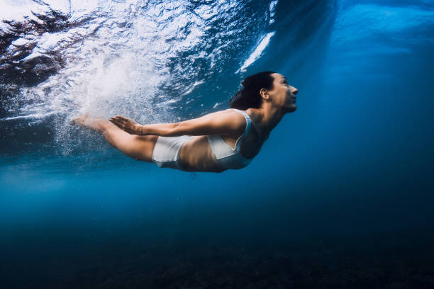 istock Woman swim underwater with crashing ocean wave. 2198007831