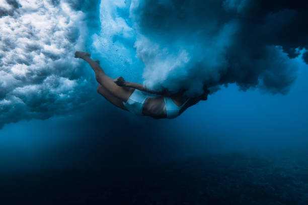 istock Woman dive without surfboard under powerful ocean wave. Duck dive under crashing wave 2198007839