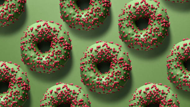 istock Creative background with green glazed donuts covered in red sprinkles on a green surface. A festive and modern design for creative projects 2198008194