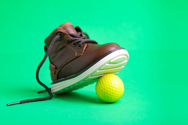 istock children's shoe and ball on a green background, close-up. Space for text. 2198008971