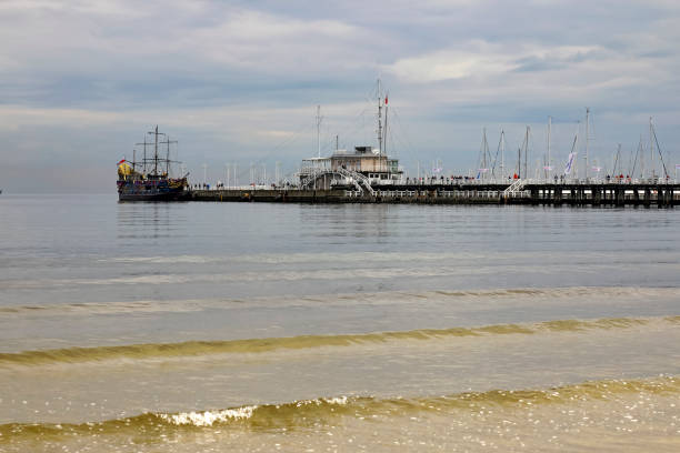 Sopot, Poland - October 7, 2024: The pier, general view, seen from the Baltic Sea beach. At the end of the pier, an artistically stylized ship named Pirat is moored.