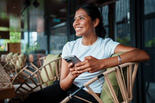 istock Smiling Woman Engaging with Smartphone in Modern Caf Setting 2198009376