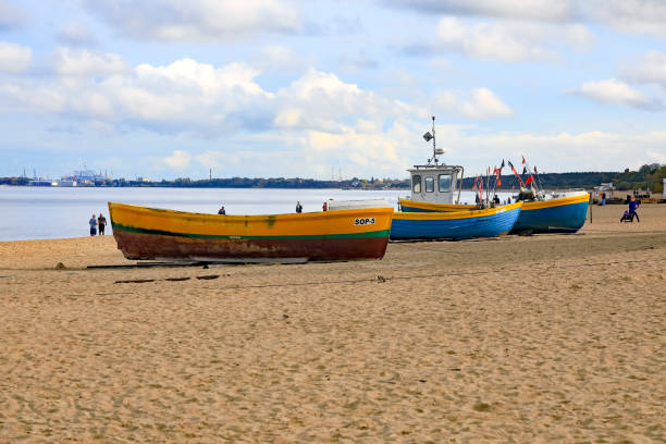 Sopot, Poland - October 9, 2024: Fishing boats have been pulled up to a sandy beach on the shore of the sea. There are only a few people walking on the beach.