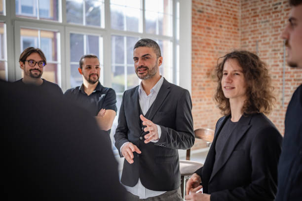 istock Group of adults engaged in joyful discussion indoors at a bright, modern venue with a rustic brick wall 2198009971