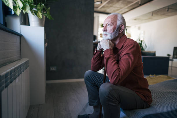 istock Unhappy elderly man sitting on the bed 2198010355