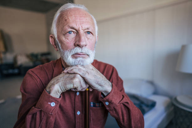 istock Unhappy elderly man sitting on the bed 2198010375
