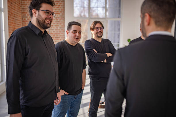 Four adults engage in lively conversation while smiling at one another in a modern indoor space filled with natural light. The atmosphere is relaxed and joyful.