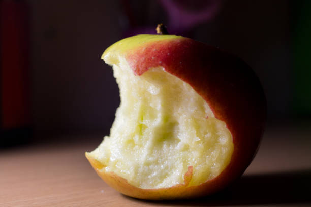 Red apple core on a wooden background. A bitten apple close-up.