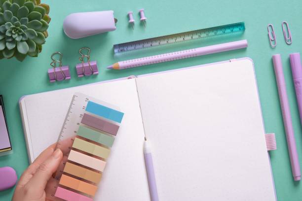istock Blank notepad page for your text in a pastel colored stationery frame. A woman's hands hold colored post-it notes. The background is mint green in color. 2198012338