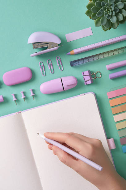 istock Blank notepad page for your text in pastel colored stationery frame. A woman is writing with a pen. The background is mint green color. 2198013628