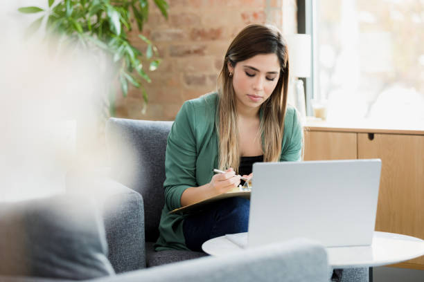 istock Young Woman Using Laptop and Taking Notes in a Modern Office 2198014648