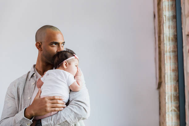 istock Tender Father Holding Infant Daughter Near Window 2198015196