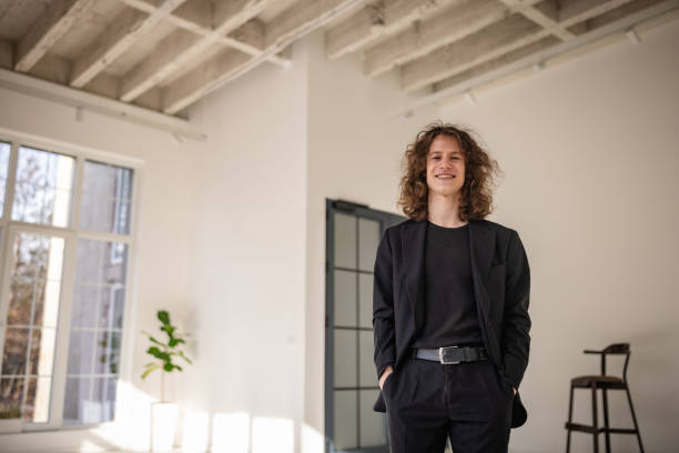 istock Smiling young man dressed in black suit stands confidently indoors in bright modern space 2198020334
