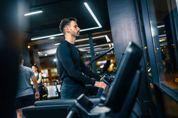 istock Young handsome man running  on a treadmill in the gym. 2198023878