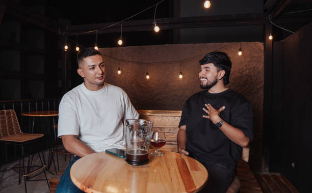 istock friends talking and laughing at a bar table with beer at night 2198024103