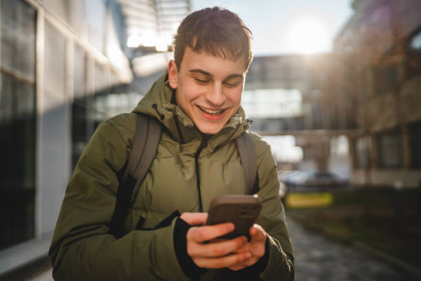 istock smiling young man walk outdoor and use mobile phone 2198025595