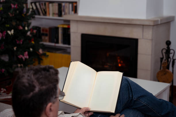 Man folding himself on a narrow armchair laying and reading a book