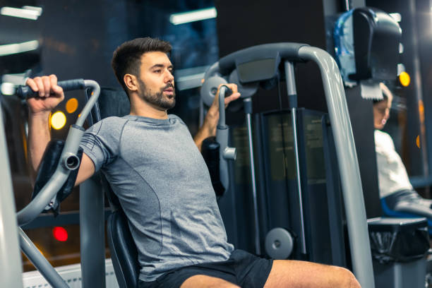 istock Sporty man doing exercise on a arm press machine in the gym. 2198027281