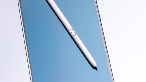 White pen is laying on a blue phone. The pen is pointing to the camera. Scene is calm and focused