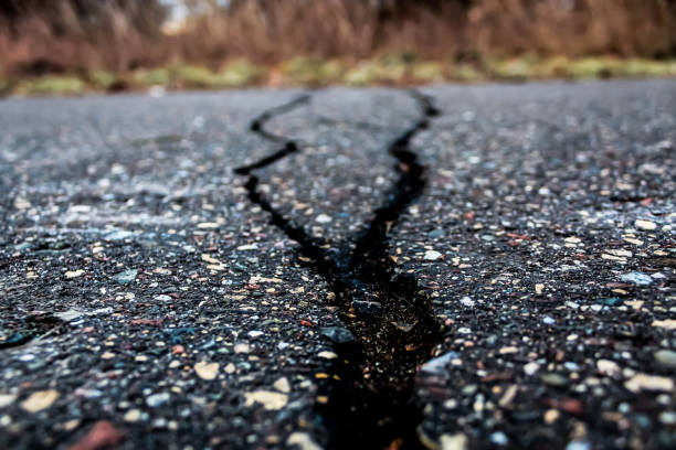 close-up of a fork in the road. long crack in pavement. abstract concept for obstacles, uncertainty, meeting challenges, danger ahead, widening gap disruption navigation construction season background