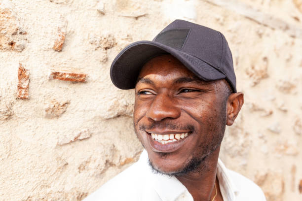 Young African man looking at the camera, with his fingers and thumbs touching  wearing casual clothing against orange background