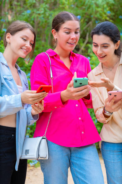 istock Excited Young Women Sharing Content on Smartphones Outdoors.Vertical 2198030406
