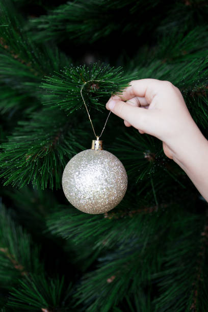 istock Childs hand decorating Christmas tree with glittering ornament 2198030628