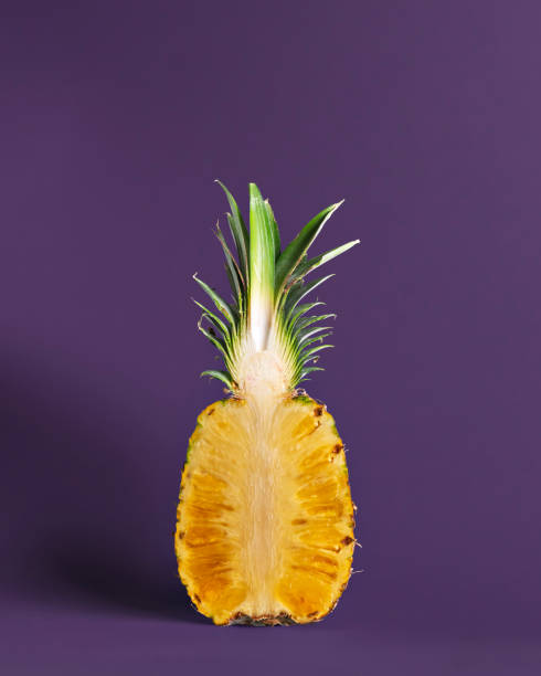istock Vertically sliced pineapple stands against a deep purple background. Tropical fruit, healthy food, and organic texture in minimal composition 2198035025