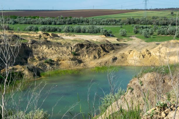 a huge blue lake in a quarry. deciduous forests and fields around. the horizon is visible. an artificial lake among fields