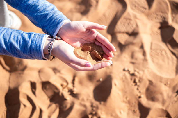 close up of children's hands with sand in their hands in the desert