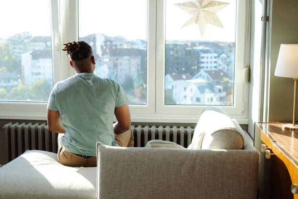 Man sitting by a window with a city view during a serene day