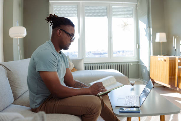 istock Man studying at home on a laptop and taking notes in a cozy room 2198040191