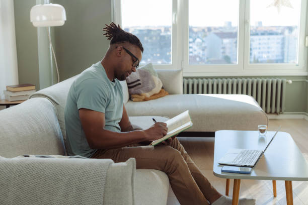 istock Man writing on a notebook while working from home in a modern living room 2198040278