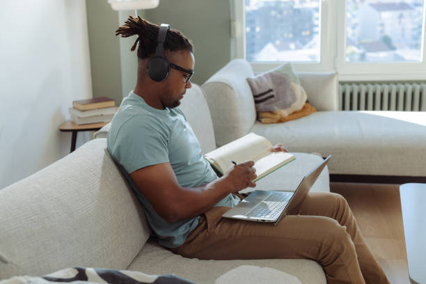 istock Man studying at home on a laptop and taking notes in a cozy room 2198040503