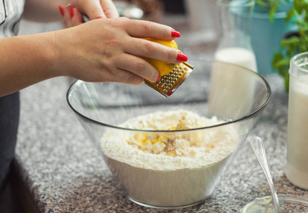 A woman preparing donuts at home, she putting the lemon zest into glass bowl