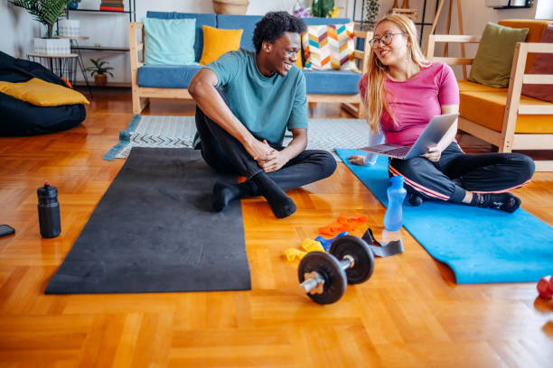 istock Friends having fun exercising together at home and talking a break while sitting on exercise mats 2198052732
