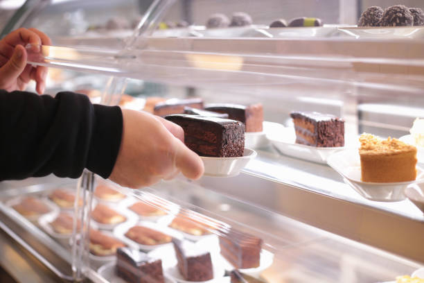 istock Customer selecting a slice of chocolate cake from bakery display 2198056912