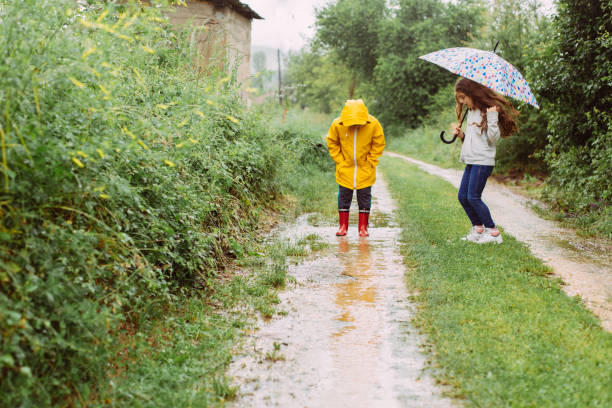 istock Playful children jumping and playing in a muddle puddle on a spring rainy day. 2198057401