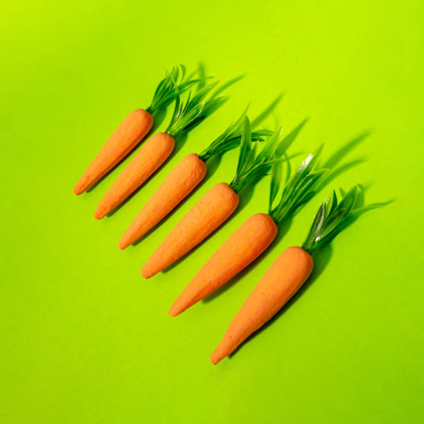 istock Carrots on pastel yellow. Minimal Easter concept. Spring minimal composition. 2198058378