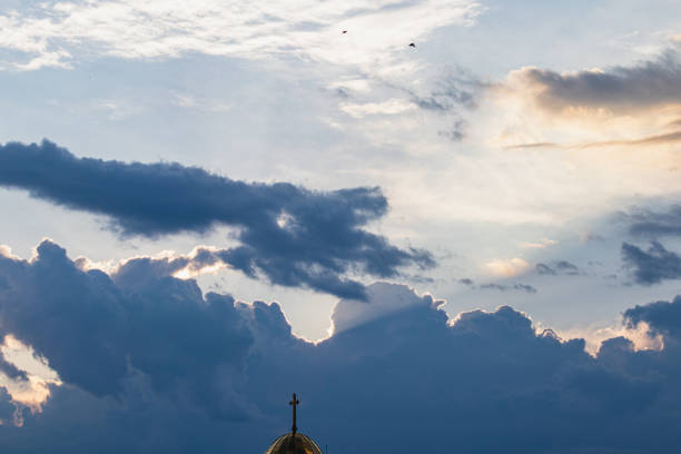 Golden sunlight dances across the morning sky, illuminating varied cloud lines. Soft shades of blue and white enhance the tranquil atmosphere, signaling the start of a new day.