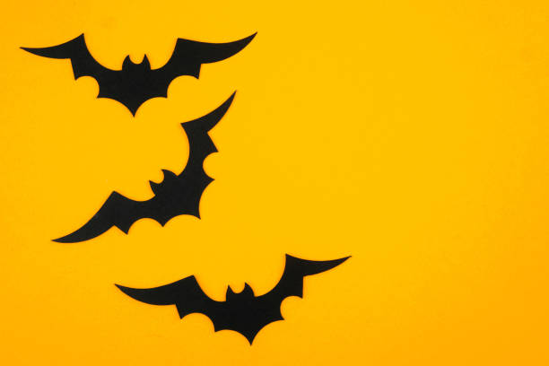 istock Three black bats flying against a bright yellow background during autumn festivities 2198065044