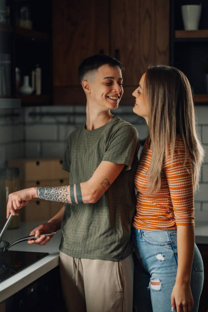 istock Lesbian couple cooking together and smiling in modern kitchen 2198065288