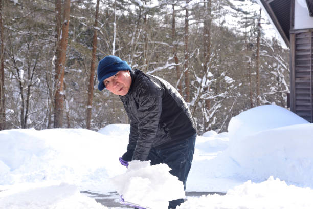 istock A smiling old man using a snow plow to remove snow in a snowy area 2198067250