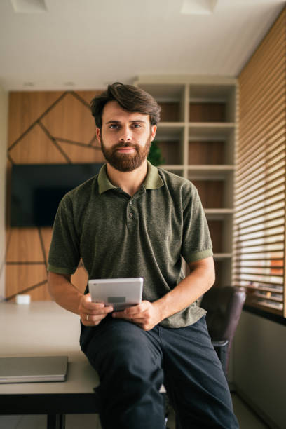 Young man looking at the camera waiting for his team at the office