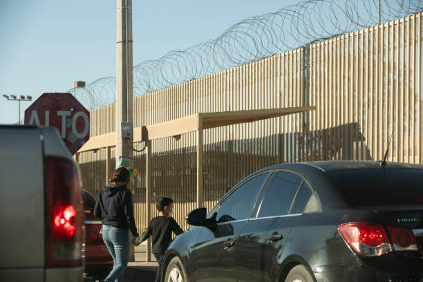 San Luis Río Colorado, Sonora, Mexico - January 3, 2022: A mother and child walk in front of the border wall at the US Port of Entry at San Luis Arizona.