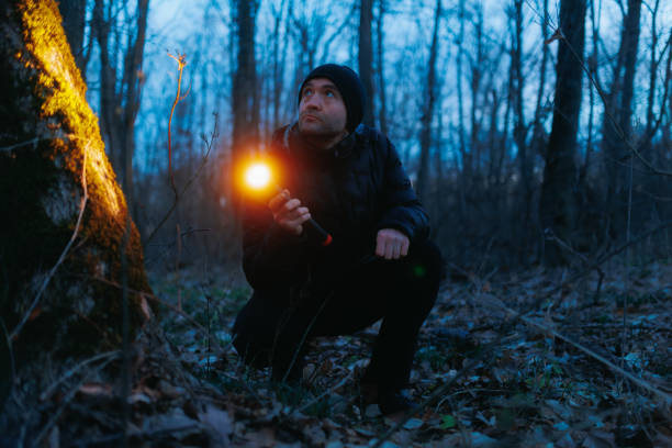 istock standing in the forest at night, a man uses a flashlight to search. 2198081715