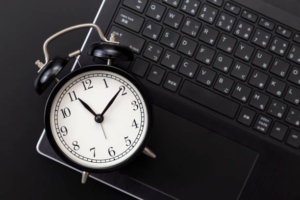 istock Laptop and clock on a black background 2198087363