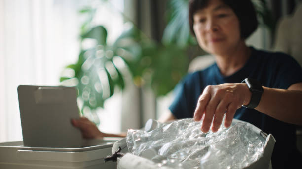 Asian mature woman separating waste plastic bottle at home.