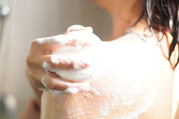 istock Woman picks up soap and rubs it on her shoulders. 2198096368