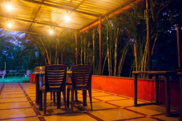 Tropical resort terrace illuminated at night with empty chairs and tables, creating a peaceful and inviting ambiance.